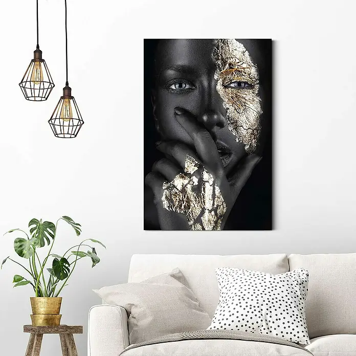 Reinders Decopanel - Woman Gold Hand, B x H: 60 x 90 cm - Nahaufnahme eines Wandbilds mit einer Frau, deren Gesicht und Hand mit Goldfolie verziert sind, montiert über einem weißen Sofa.
