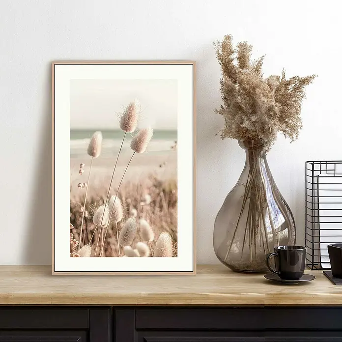 Reinders Bild Slim Frame Wood - Romantic Grasses, B x H: 20 x 30 cm - Dekoratives Stillleben mit einem gerahmten Pflanzenbild, einer Vase mit Trockenblumen und einer Kaffeetasse auf einem Sideboard.