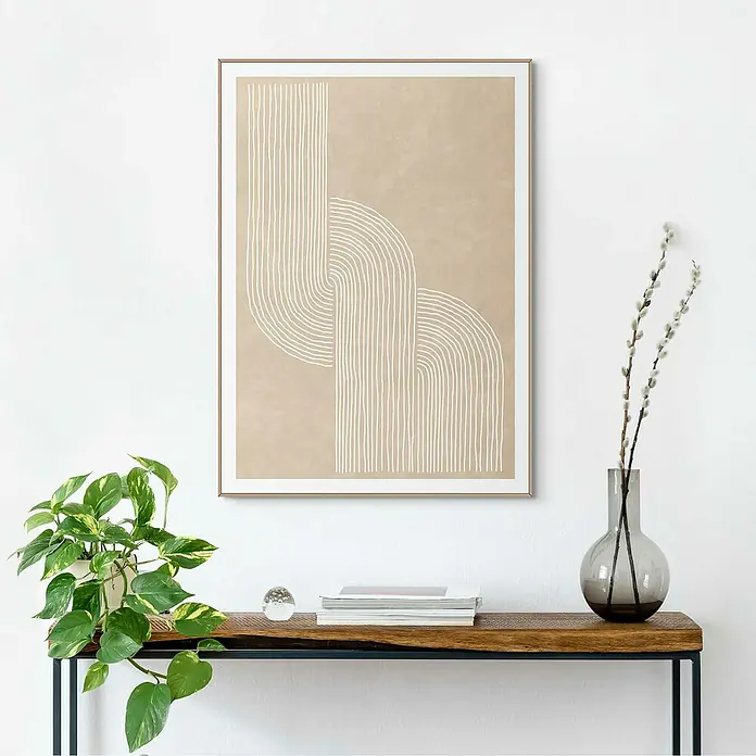 Reinders Bild Slim Frame Wood - Sandy Knot, B x H: 50 x 70 cm - Ein beiges, gerahmtes Kunstwerk mit abstraktem weißen Liniendesign hängt über einem Holztisch mit Pflanzen und Dekorationen.