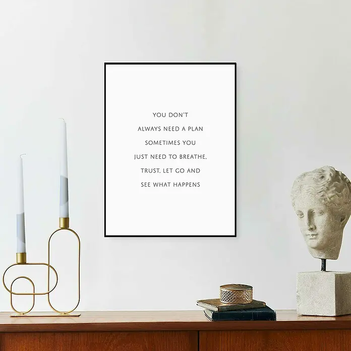 Reinders Bild Slim Frame Black - What Happen, B x H: 30 x 40 cm - Ein minimalistisches gerahmtes Poster mit motivierendem Text, neben Kerzen und einer Skulptur auf einer Holzkommode.