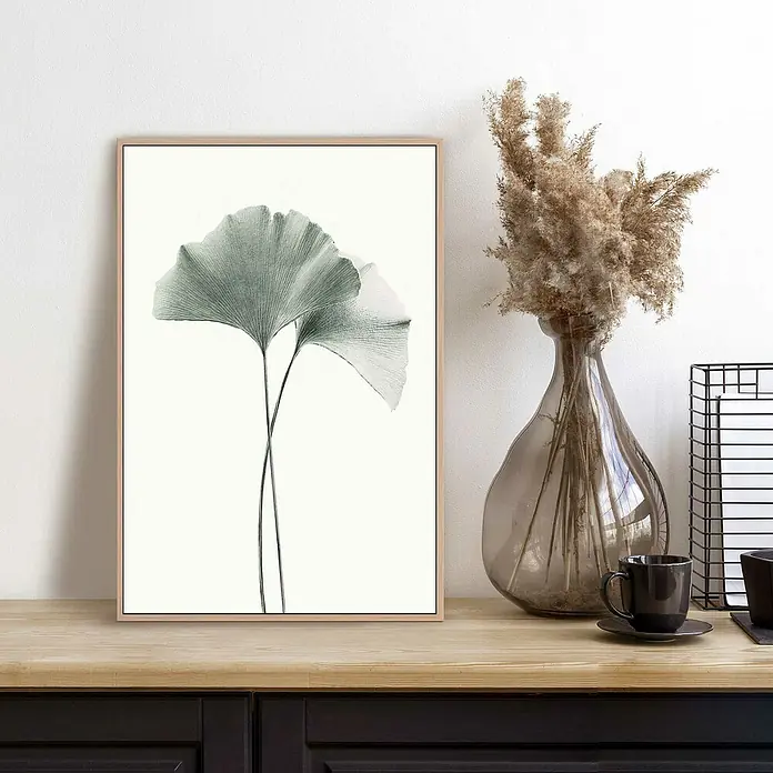 Reinders Bild Slim Frame Wood - Gingko, B x H: 20 x 30 cm - Stillleben mit einem gerahmten Pflanzenbild, einer Vase mit Trockenblumen und einer Tasse auf einem Holzschrank.