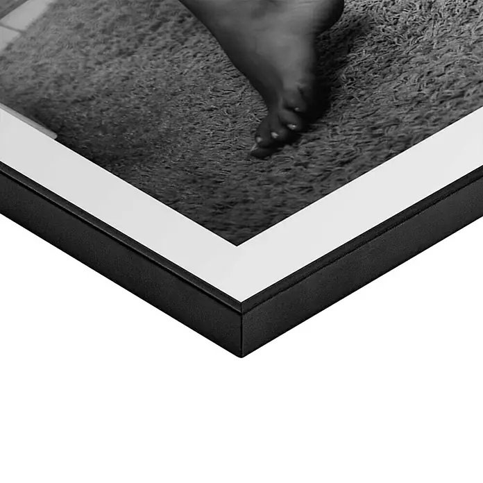 Reinders Bild Slim Frame Black - Getting Dressed, B x H: 50 x 70 cm - Nahaufnahme eines gerahmten Fotos, das einen Fuß auf einem Teppich zeigt, mit Fokus auf die Textur und das Detail des Bildes.
