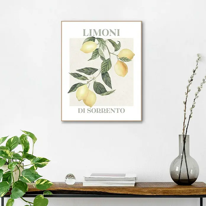 Reinders Bild Slim Frame Wood - Limoni, B x H: 40 x 50 cm - Ein gerahmtes Wandbild "Limoni di Sorrento" mit Zitronenmotiv hängt über einem Holztisch, dekoriert mit Pflanzen und Büchern.