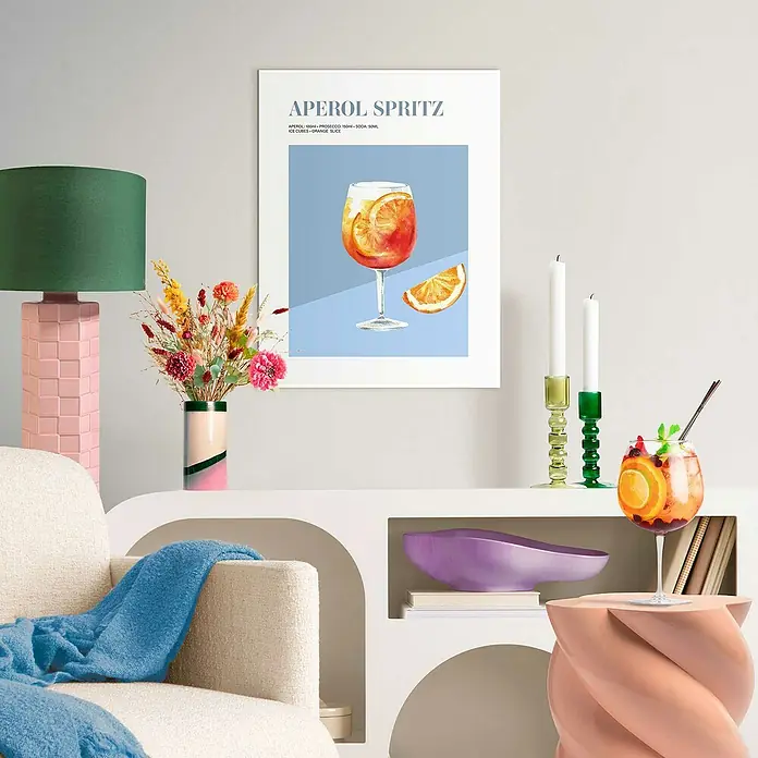 Reinders Bild Slim Frame White - Aperol, B x H: 30 x 40 cm - Ein Aperol Spritz Poster an einer Wand, neben einem grünen Lampenschirm und einer Vase, die eine gemütliche und stilvolle Atmosphäre schafft.