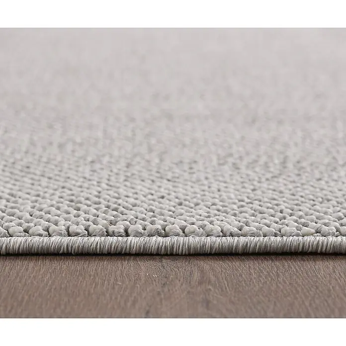 Flachgewebeteppich Loom - Silber, Durchmesser: 160 cm, 100 % Polypropylen - Nahaufnahme eines grauen Teppichs mit einem strukturierten Design und einer ordentlichen Kante, der auf einem Holzboden liegt.