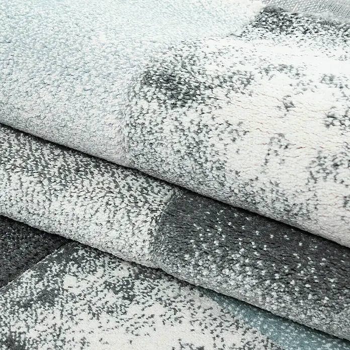 Kurzflorteppich Hawaii 1710 - Blau, 340 x 240 cm, 100 % Polypropylen - Nahaufnahme von gestapelten, weichen Teppichen mit abstraktem Muster in Grau- und Weißtönen, die Textur und Komfort betonen.