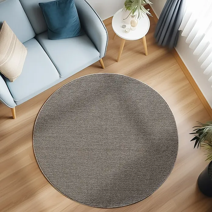 Flachgewebeteppich Loom - Braun, Durchmesser: 160 cm, 100 % Polypropylen - Ein gemütlicher Raum mit einem runden Teppich, einem hellblauen Sofa und einem kleinen Tisch, der eine warme und einladende Atmosphäre schafft.