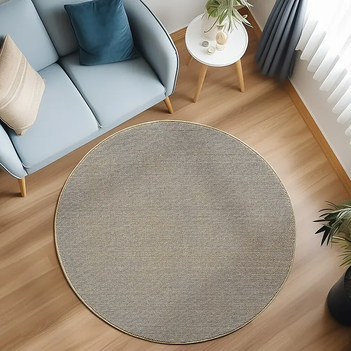 Flachgewebeteppich Loom - Beige, Durchmesser: 120 cm, 100 % Polypropylen - Ein runder Teppich mit einem subtilen Punktmuster liegt unter einem blauen Sofa und einem Beistelltisch mit Topfpflanze.