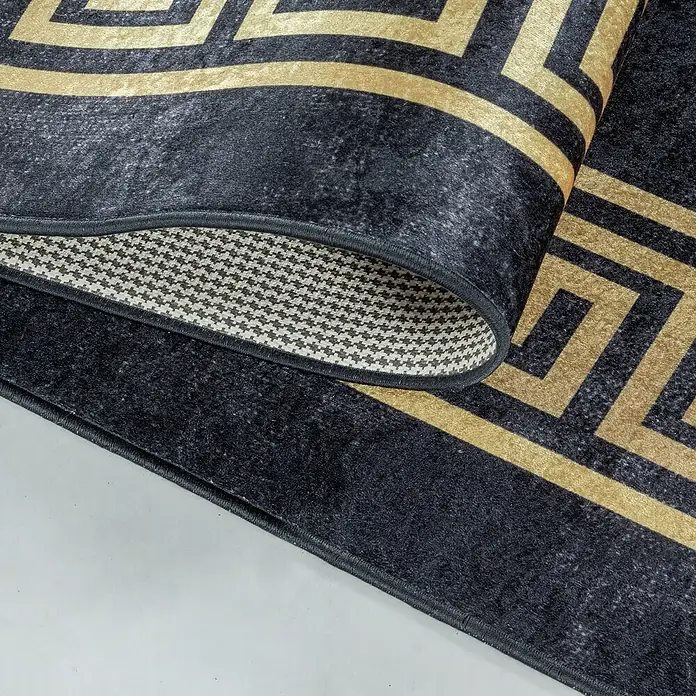 Flachgewebeteppich Fiesta - Schwarz/Gold, 150 x 80 cm, 100 % Polyester - Ein luxuriöser, gerollter Teppich mit einem schwarzen und goldenen geometrischen Muster, das Eleganz und Komfort vereint.