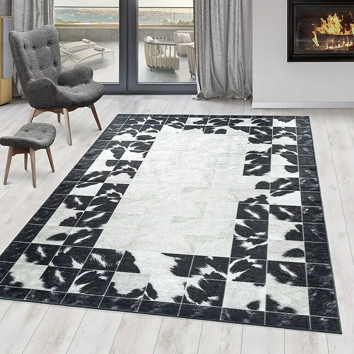 Flachgewebeteppich Fiesta - Schwarz/Weiß, 290 x 200 cm, 100 % Polyester - Ein rechteckiger Teppich mit einem schwarz-weißen Kuhfellmuster und einem helleren Innenbereich, der eine moderne Atmosphäre schafft.