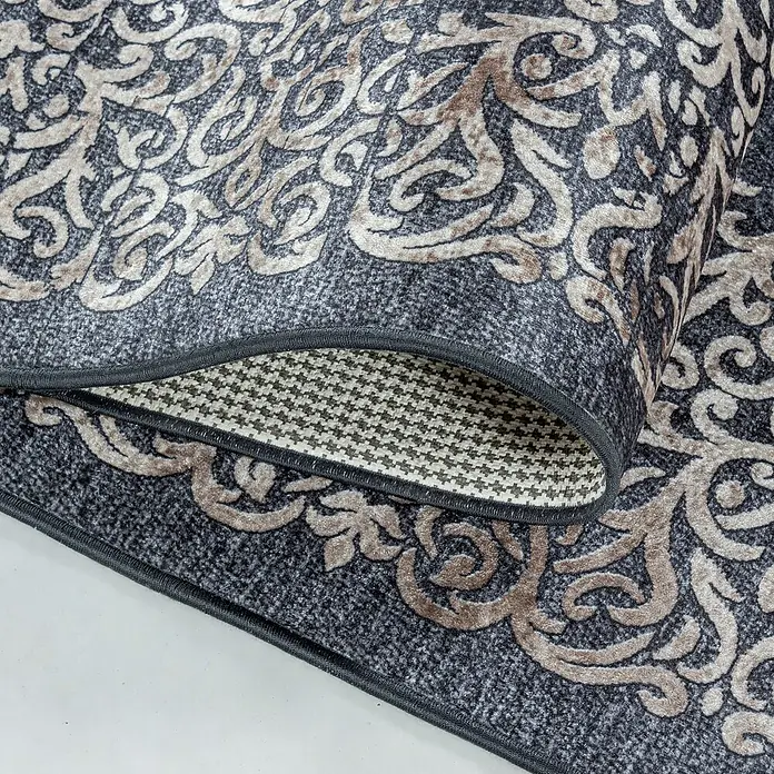 Flachgewebeteppich Fiesta - Schwarz, 150 x 80 cm, 100 % Polyester - Nahaufnahme eines grauen Teppichs mit gewebtem Design und aufgerollter Ecke, der die Textur hervorhebt.