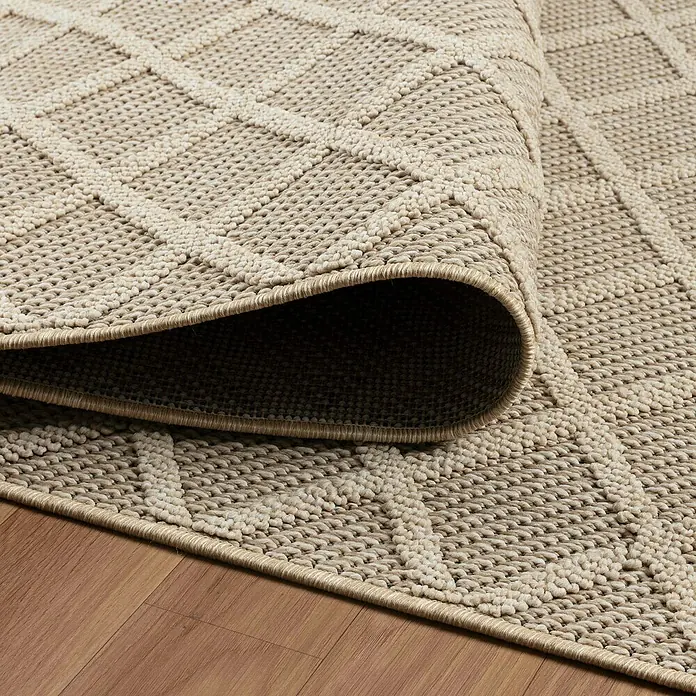 Outdoor-Teppich Patara V - Beige, 200 x 140 cm, 100 % Polypropylen - Detailaufnahme eines beigen Teppichs mit geometrischem Muster, teilweise aufgerollt, der seine Textur und Webart zeigt.