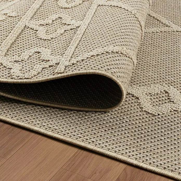 Outdoor-Teppich Patara II - Beige, 150 x 80 cm, 100 % Polypropylen - Detailansicht eines beigen Teppichs mit dekorativem Muster und gerolltem Rand auf einem Holzboden.