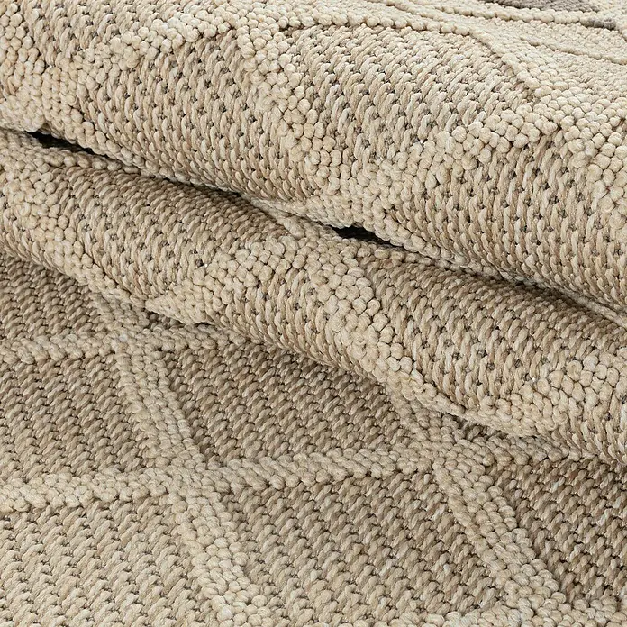 Outdoor-Teppich Patara V - Beige, 200 x 140 cm, 100 % Polypropylen - Nahaufnahme eines gerollten, beigen Teppichs mit auffälliger Textur und einem dezenten, geometrischen Muster. Ideal für Wohnräume.