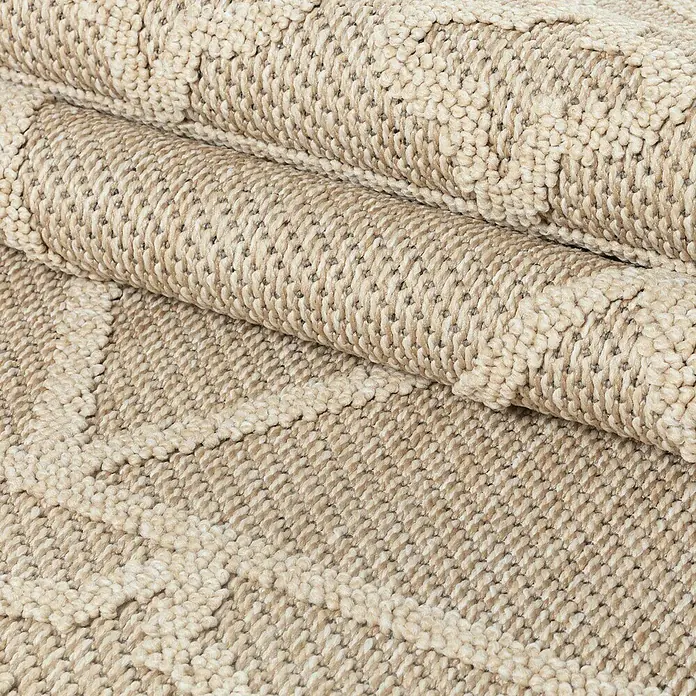 Outdoor-Teppich Patara II - Beige, 150 x 80 cm, 100 % Polypropylen - Nahaufnahme eines gerollten, beigen Teppichs mit einer texturierten Oberfläche und einem subtilen Muster. Ideal für Wärme und Stil im Raum.