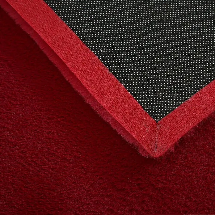 Hochflorteppich Pouffy - Rot, 290 x 200 cm, 100 % Polyester - Nahaufnahme eines roten Teppichs mit schwarzer, rutschfester Unterseite und roter Einfassung.
