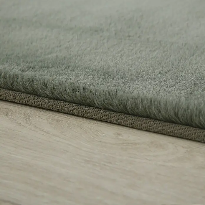 Hochflorteppich Pouffy - Grün, 170 x 120 cm, 100 % Polyester - Nahaufnahme eines grauen Teppichs mit weicher Textur, der auf einem hellen Holzboden liegt. Perfekt für ein gemütliches Zuhause.