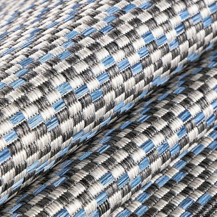 Outdoor-Teppich Sunny VII - Grau, 170 x 120 cm, 100 % Polypropylen - Nahaufnahme eines strukturierten, gerollten Outdoor-Teppichs mit blau-grau-schwarzem Webmuster, ideal für Balkon und Terrasse.