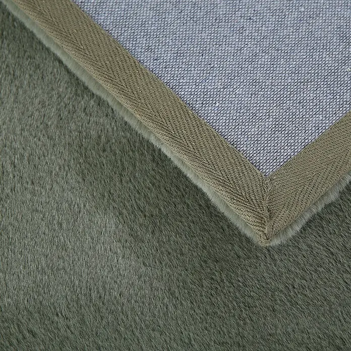 Hochflorteppich Pouffy - Grün, 170 x 120 cm, 100 % Polyester - Detailansicht eines Teppichs mit olivgrünem Flor, einer braunen Bordüre und einer grauen Stoffrückseite.