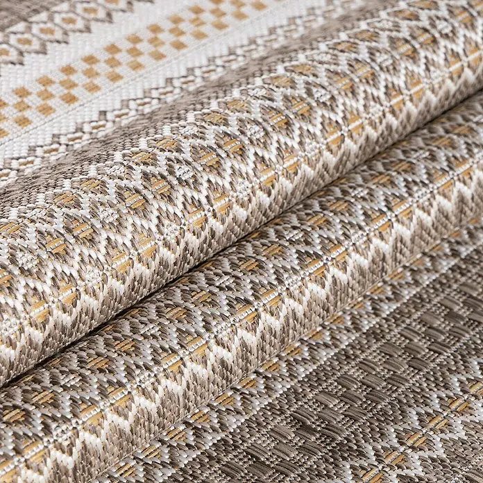 Outdoor-Teppich Sunny V - Beige, 150 x 80 cm, 100 % Polypropylen - Nahaufnahme eines Stapels dekorativer, gemusterter Stoffe in verschiedenen Braun- und Beigetönen, ideal für Heimtextilien.
