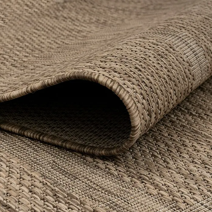 Outdoor-Teppich Relax - Braun, 250 x 80 cm, 100 % Polypropylen - Detailaufnahme eines beigefarbenen gewebten Teppichs, der aufgerollt ist und die Textur und Webart des Teppichs hervorhebt.