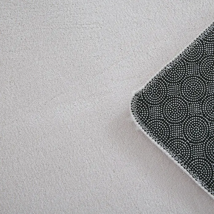 Kurzflorteppich Sky - Creme, 150 x 80 cm, 100 % Polyester - Nahaufnahme einer hellgrauen Teppichoberfläche, die Textur und Verarbeitung des Materials hervorhebt. Detailansicht der Rückseite mit rutschfestem Muster.