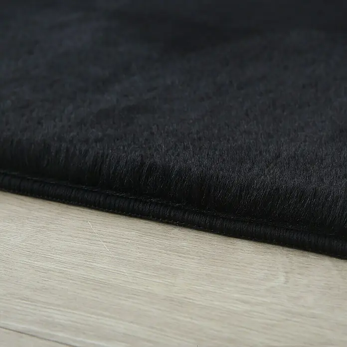 Hochflorteppich Pouffy - Schwarz, 150 x 80 cm, 100 % Polyester - Detailaufnahme eines schwarzen Teppichs, der dessen weiche Textur und die hochwertige Verarbeitung zeigt.