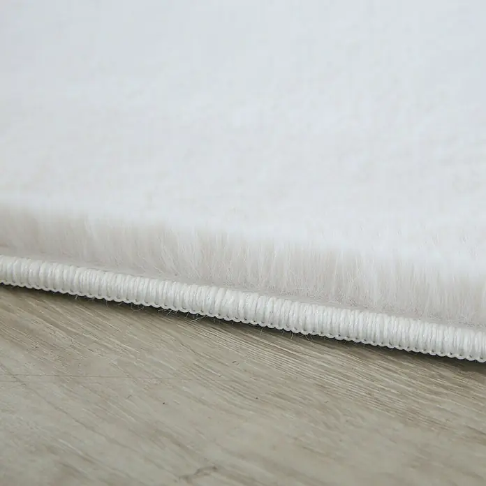 Hochflorteppich Pouffy - Creme, 200 x 140 cm, 100 % Polyester - Detailaufnahme eines weißen Teppichs mit weicher Textur und sauberer Kante, ideal für Wohnräume.