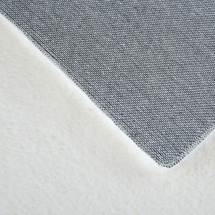 Hochflorteppich Pouffy - Creme, 200 x 140 cm, 100 % Polyester - Detailaufnahme eines Teppichs mit flauschiger Oberfläche und gewebter Unterseite, die Textur und Kontrast hervorhebt.