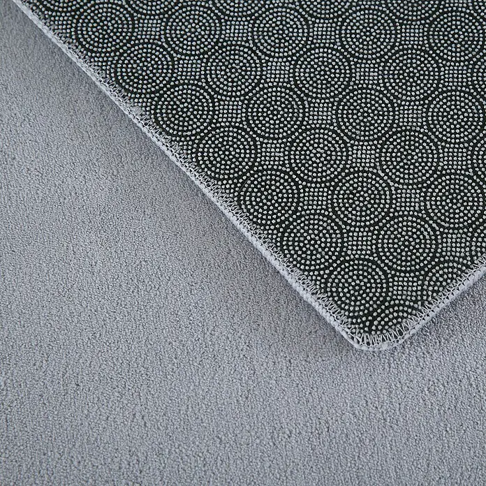 Kurzflorteppich SkySilber, 340 x 240 cm, 100 % Polyester - Nahaufnahme einer strukturierten, rutschfesten Teppichrückseite mit Punktmuster für sicheren Halt auf glatten Böden.