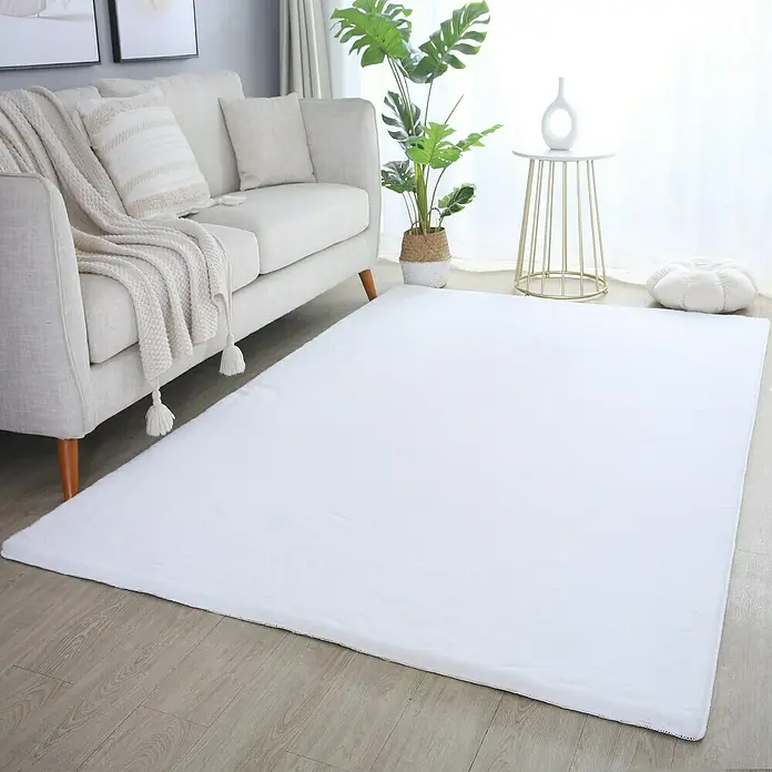 Hochflorteppich Pouffy - Weiß, 250 x 80 cm, 100 % Polyester - Ein weißer Teppich liegt im Wohnzimmer vor einem hellen Sofa, einer Pflanze und einem Beistelltisch, der dem Raum eine moderne Note verleiht.