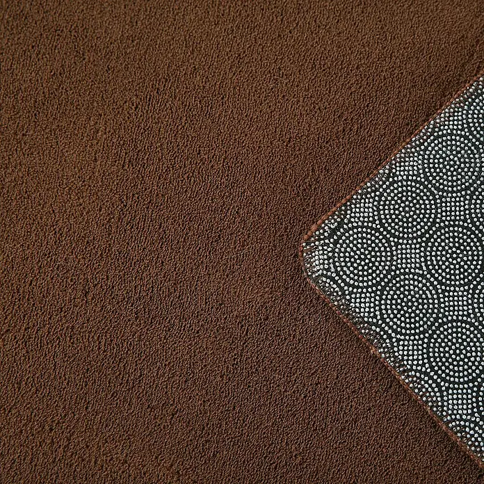 Kurzflorteppich Sky - Braun, 200 x 140 cm, 100 % Polyester - Nahaufnahme eines braunen, weichen Teppichs mit einer rutschfesten Unterseite, ideal für Komfort und Sicherheit im Haus.