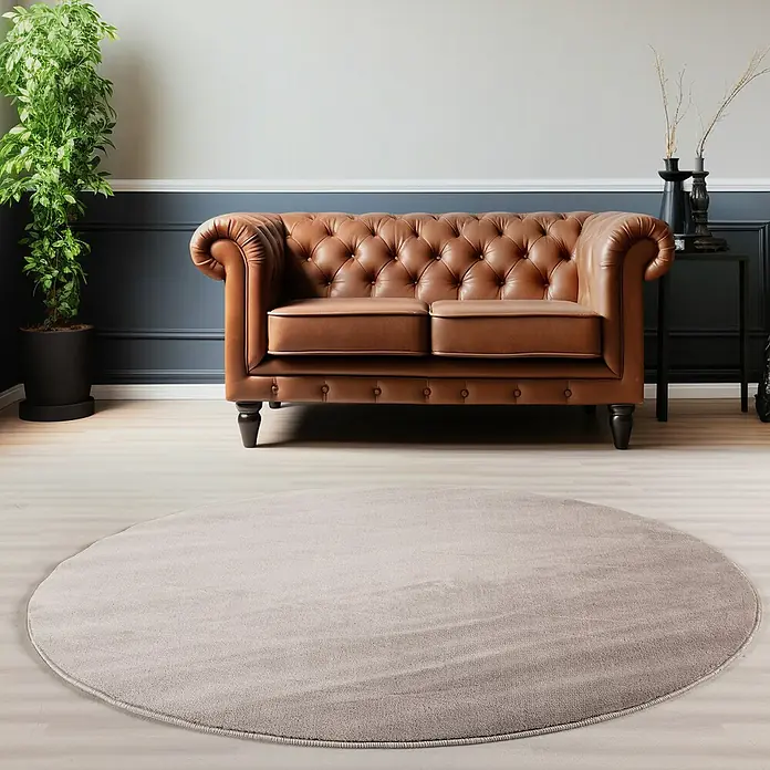 Kurzflorteppich Sky - Beige, Durchmesser: 120 cm, 100 % Polyester - Einladendes Wohnzimmer mit einem braunen Chesterfield-Sofa und einem runden, grauen Teppich, der den Raum optisch aufwertet.