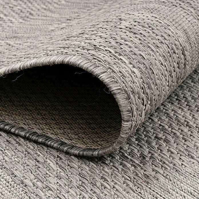 Outdoor-Teppich Relax - Grau, 200 x 140 cm, 100 % Polypropylen - Nahaufnahme eines gerollten grauen Outdoor-Teppichs mit gewebter Textur und schlichter Bordüre, ideal für Terrasse oder Balkon.