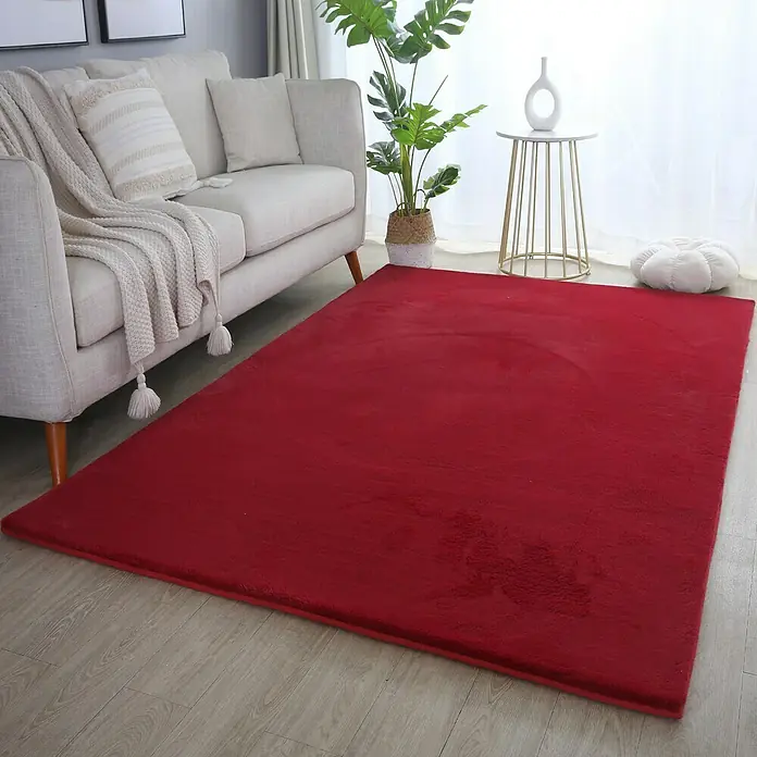 Hochflorteppich Pouffy - Rot, 290 x 200 cm, 100 % Polyester - Ein roter Teppich liegt vor einem Sofa, der dem Wohnzimmer eine warme und gemütliche Note verleiht.