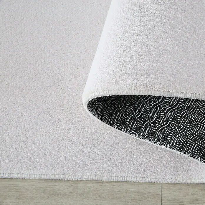 Kurzflorteppich Sky - Creme, 150 x 80 cm, 100 % Polyester - Detailaufnahme eines weißen Badteppichs mit rutschfester Unterseite. Die flauschige Textur und die hochwertige Verarbeitung sind gut erkennbar.