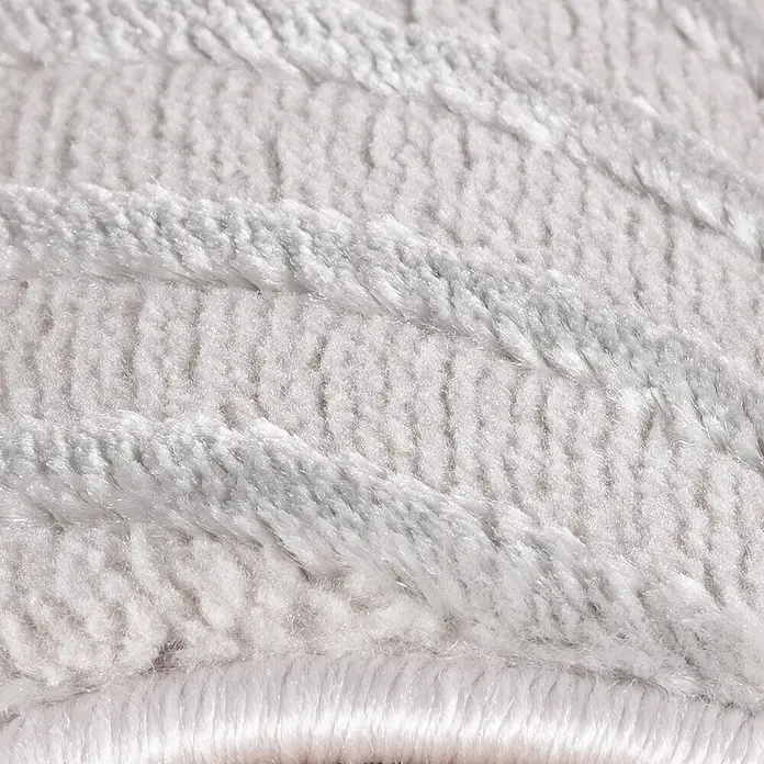Kurzflorteppich Sahara IV - Silber, 370 x 280 cm, 100 % Polypropylen - Nahaufnahme eines flauschigen, grauen Teppichs mit reliefartigen Streifen. Das Material wirkt weich und einladend.