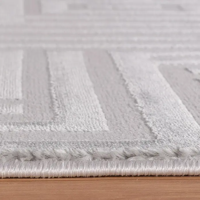 Kurzflorteppich Sahara III - Silber, 170 x 120 cm, 100 % Polypropylen - Nahaufnahme eines hellgrauen Teppichs mit einem geometrischen Muster, der eine weiche Textur und einen sauberen Rand zeigt.