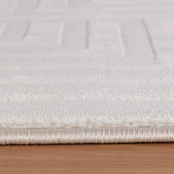 Kurzflorteppich Sahara III - Creme, 170 x 120 cm, 100 % Polypropylen - Nahaufnahme eines weißen Teppichs mit geometrischem Muster. Der Teppich liegt auf einem Holzboden.
