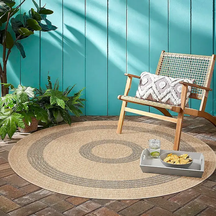 Outdoor-Teppich Comilla I - Schwarz, Durchmesser: 80 cm, 100 % Polypropylen - Ein runder, geflochtener Teppich im Freien mit konzentrischen Kreisen in Beige- und Grautönen, der eine gemütliche Atmosphäre schafft.