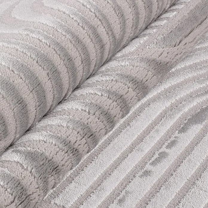 Kurzflorteppich Sahara I - Silber, 250 x 80 cm, 100 % Polypropylen - Detailansicht einer gerollten, weichen, grau gestreiften Kuscheldecke, die Wärme und Komfort für gemütliche Stunden verspricht.