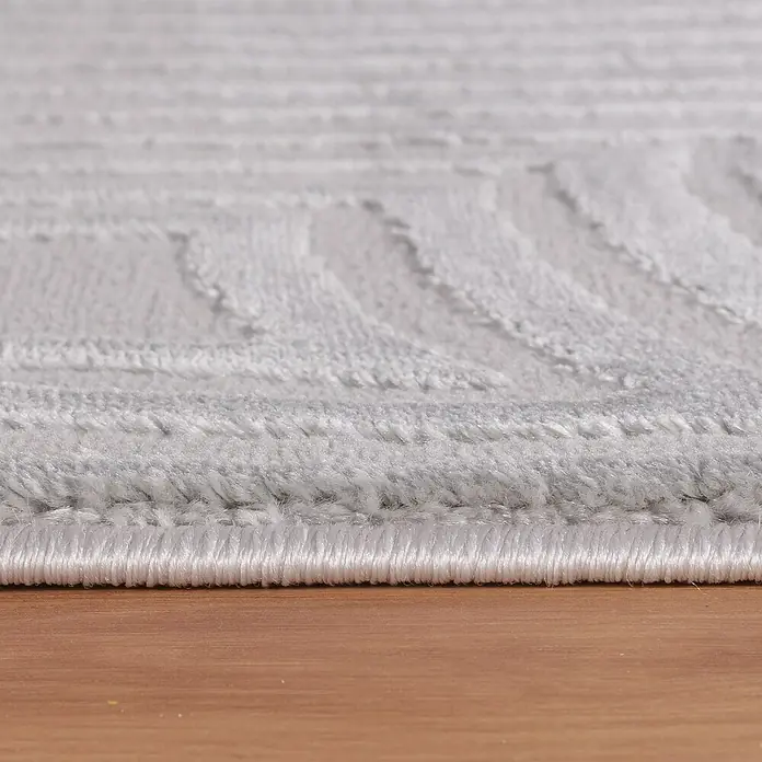Kurzflorteppich Sahara II - Silber, 170 x 120 cm, 100 % Polypropylen - Nahaufnahme eines hellgrauen Teppichs mit geometrischem Muster, der auf einem Holzboden liegt.