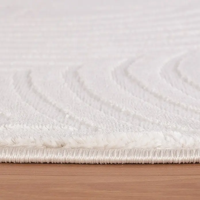 Kurzflorteppich Sahara II - Creme, 200 x 140 cm, 100 % Polypropylen - Nahaufnahme eines weißen Teppichs mit subtilem Muster und sauberer Kante, der auf einem Holzboden liegt.