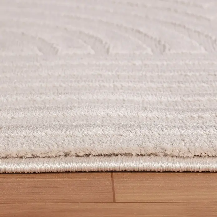 Kurzflorteppich Sahara I - Beige, 250 x 80 cm, 100 % Polypropylen - Nahaufnahme eines elfenbeinfarbenen Teppichs mit gewebtem Design und gekettelten Kanten auf einem Holzboden.