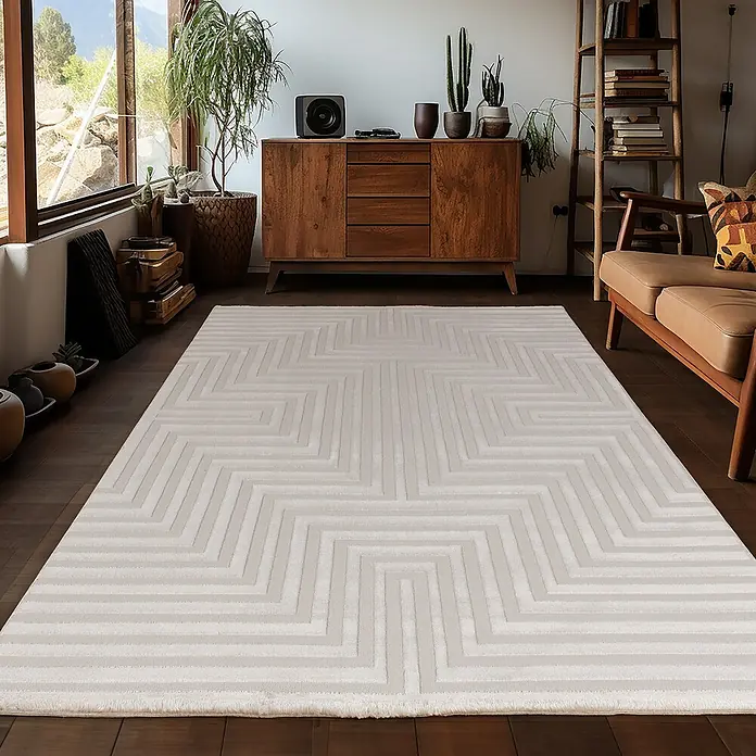 Kurzflorteppich Sahara V - Beige, 170 x 120 cm, 100 % Polypropylen - Ein hellgrauer Teppich mit geometrischem Zickzackmuster liegt in einem stilvollen Wohnzimmer. Der Teppich verleiht dem Raum eine moderne Note.