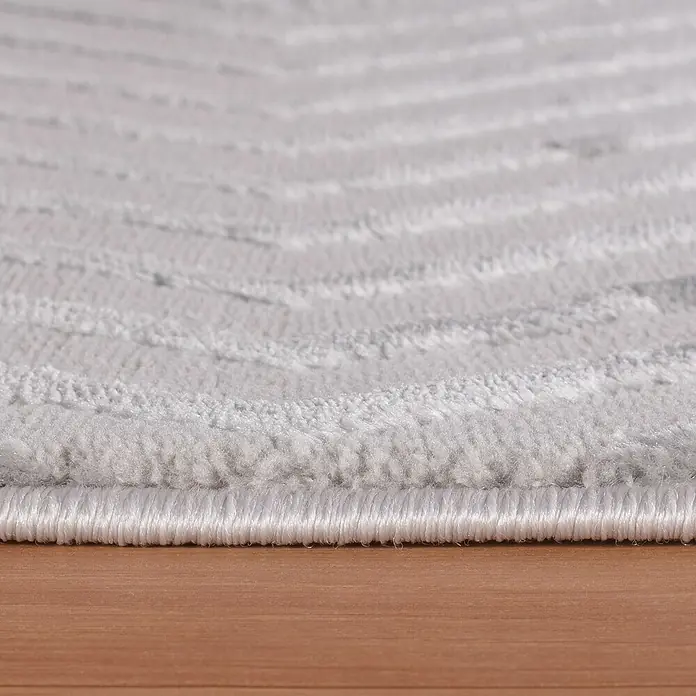 Kurzflorteppich Sahara IV - Silber, 370 x 280 cm, 100 % Polypropylen - Nahaufnahme eines grauen Teppichs mit subtilem Muster, der eine weiche Textur und eine saubere Kante zeigt.
