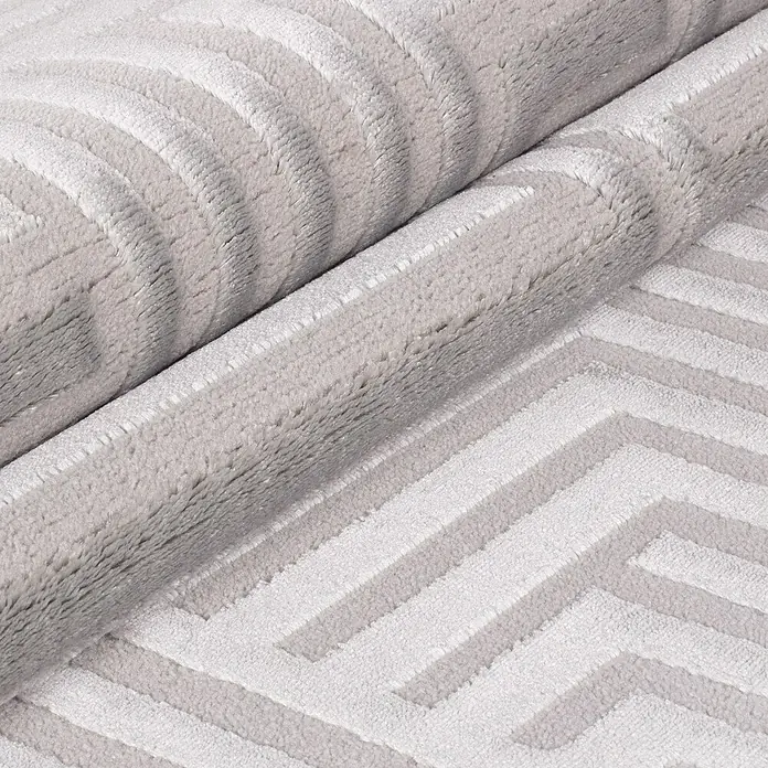Kurzflorteppich Sahara III - Silber, 170 x 120 cm, 100 % Polypropylen - Nahaufnahme eines gerollten Teppichs mit geometrischem Muster, weicher Textur und neutralen Farbtönen, ideal für modernes Wohnambiente.
