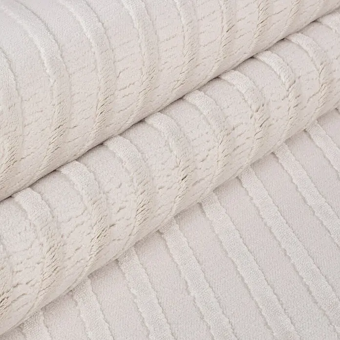 Kurzflorteppich Sahara IV - Creme, 230 x 160 cm, 100 % Polypropylen - Nahaufnahme eines cremefarbenen Stoffes mit vertikalen Rippen, der weich und einladend wirkt. Perfekt für gemütliche Wohnaccessoires.
