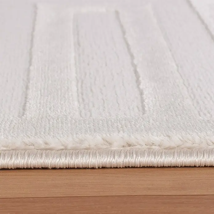 Kurzflorteppich Sahara V - Creme, 200 x 140 cm, 100 % Polypropylen - Nahaufnahme eines weichen, weißen Teppichs mit strukturiertem Muster und sauberer Kante auf einem Holzboden.