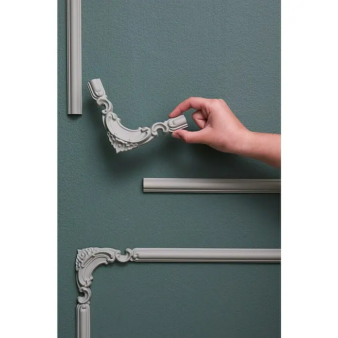 Nmc Decoflair Eckelement Eckteil Viertelbogen für Wandleiste CL2 - 4 Stk., Passend für: Nmc Decoflair Zierprofil Wandleiste CL2 - Nahaufnahme von Zierleisten an einer Wand, wobei ein Eckstück von einer Hand gehalten wird.
